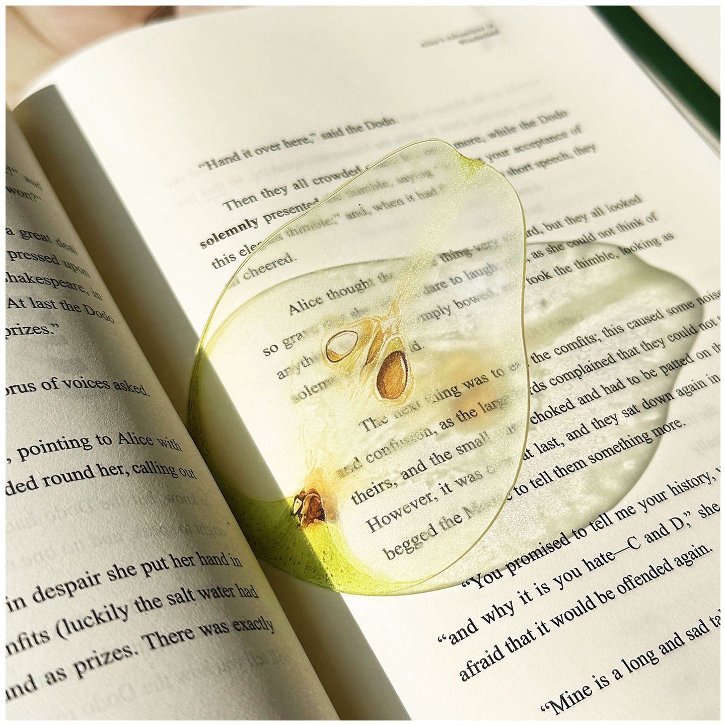Pear-shaped transparent bookmark placed inside an open book.