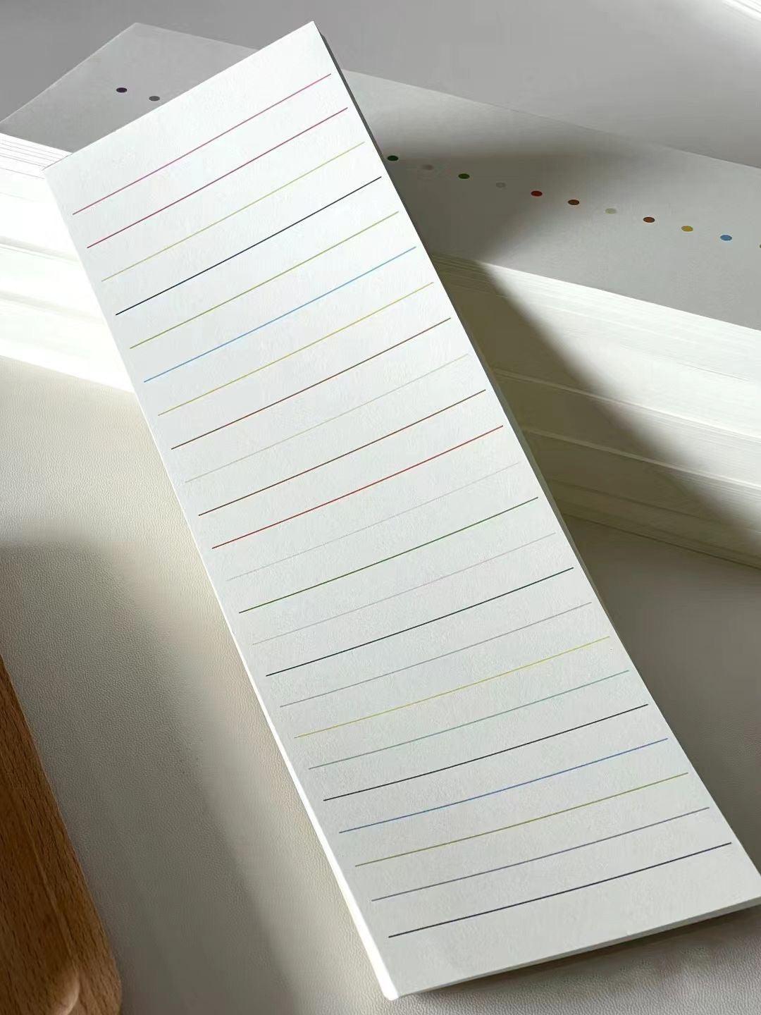 Minimal white lined notepad with subtle multicolored lines, shown as stacked writing pages in natural light.