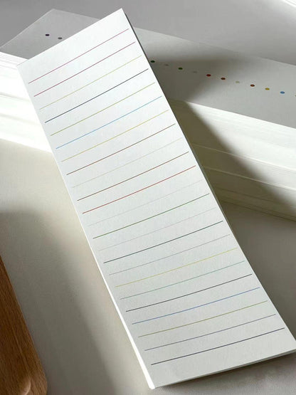 Minimal white lined notepad with subtle multicolored lines, shown as stacked writing pages in natural light.