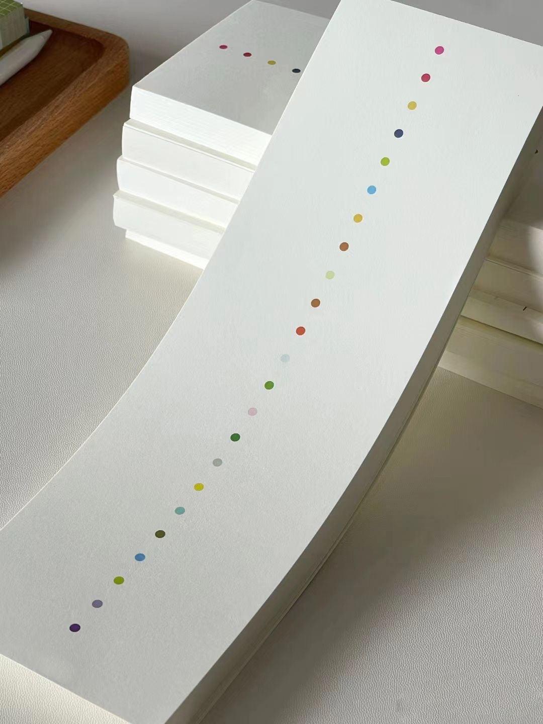 White minimalist notepad with multicolored dot pattern on the cover.