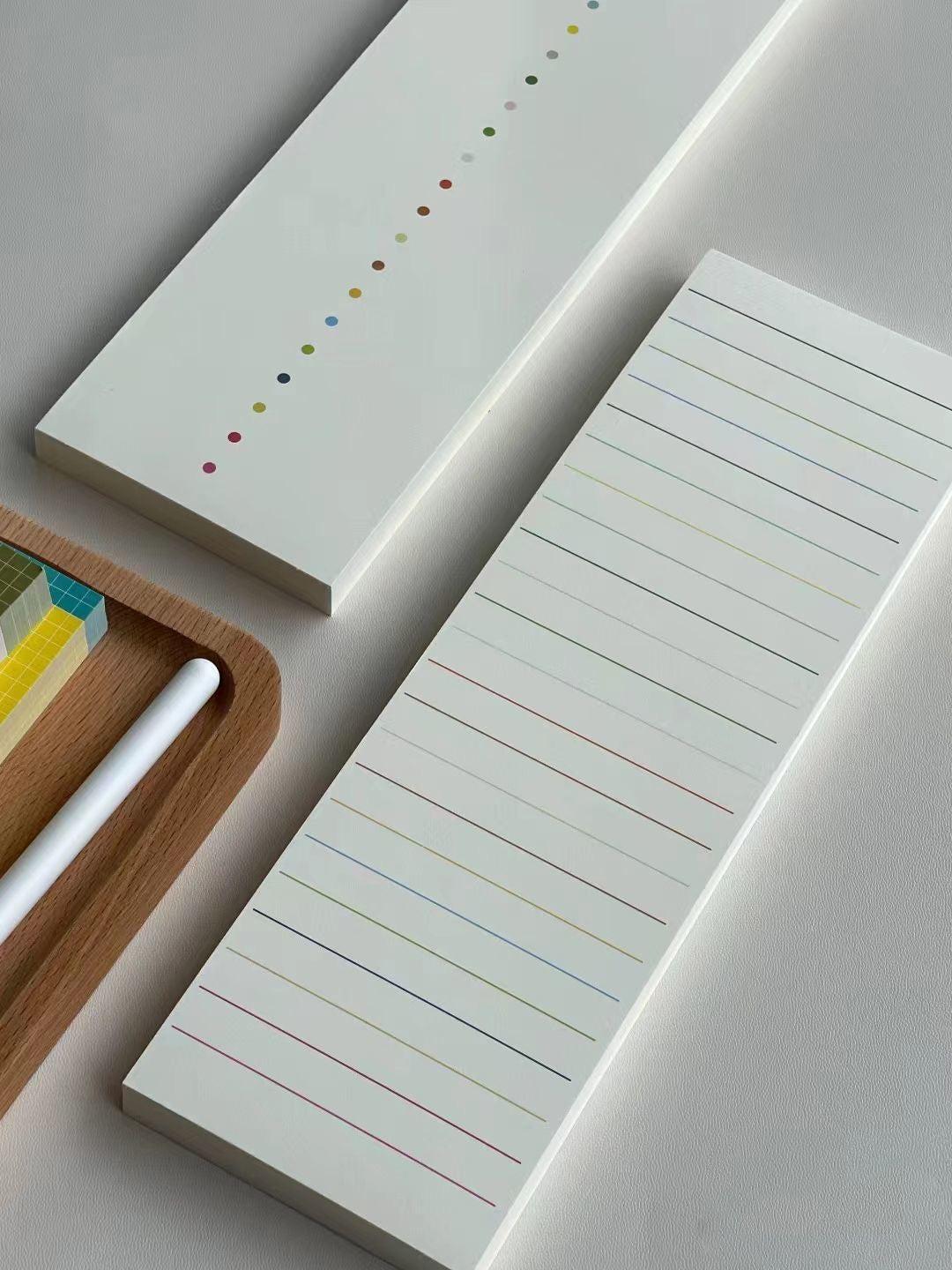 Two rectangular notepads with lined and dot patterns on a light gray surface.