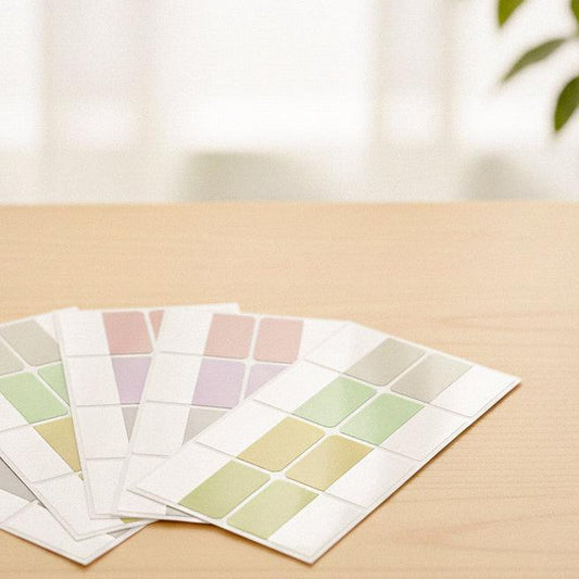 Pastel color label stickers arranged on a wooden desk in a clean, minimal setting.