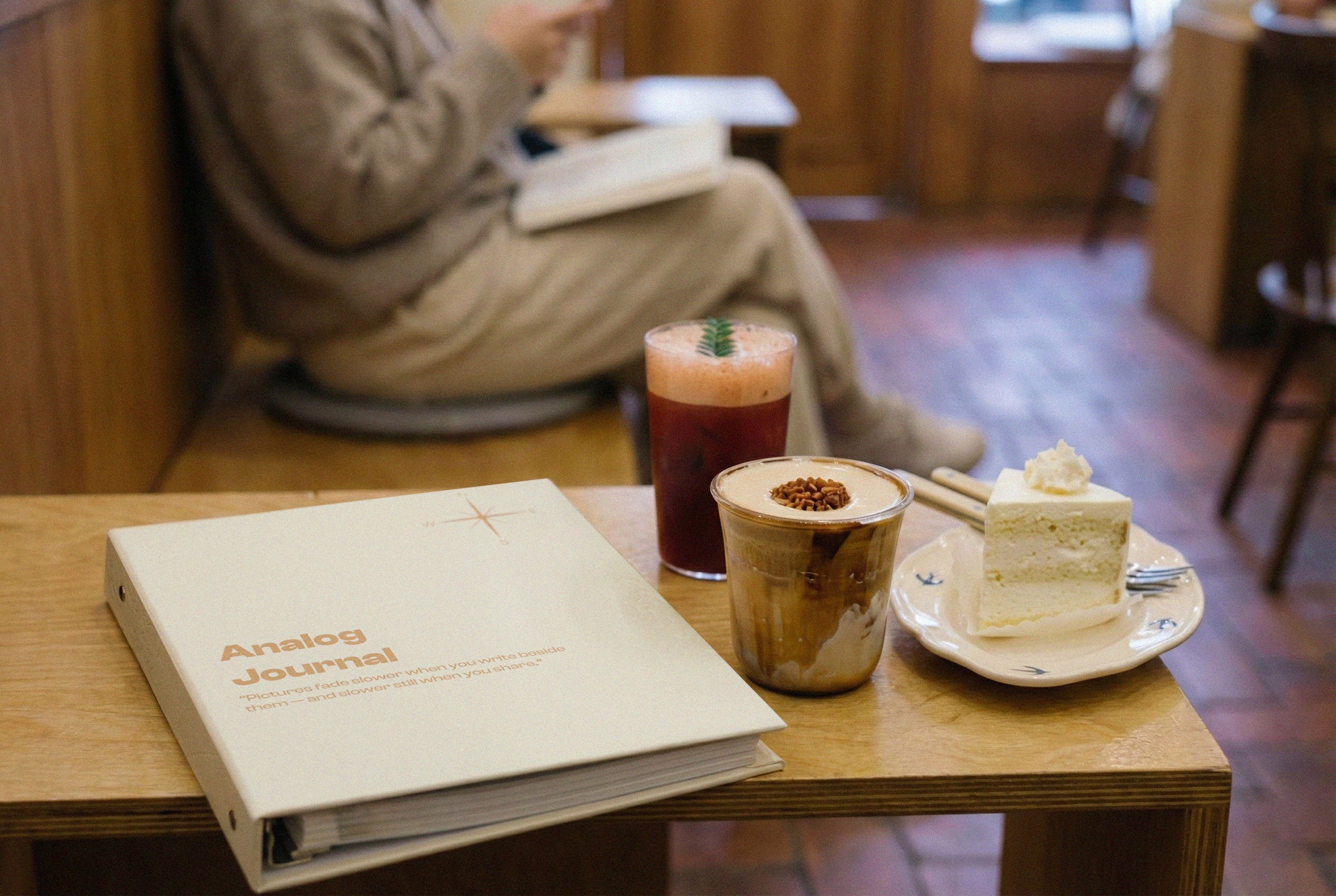 PostRush analog journal placed on a coffee shop table next to drinks and dessert.