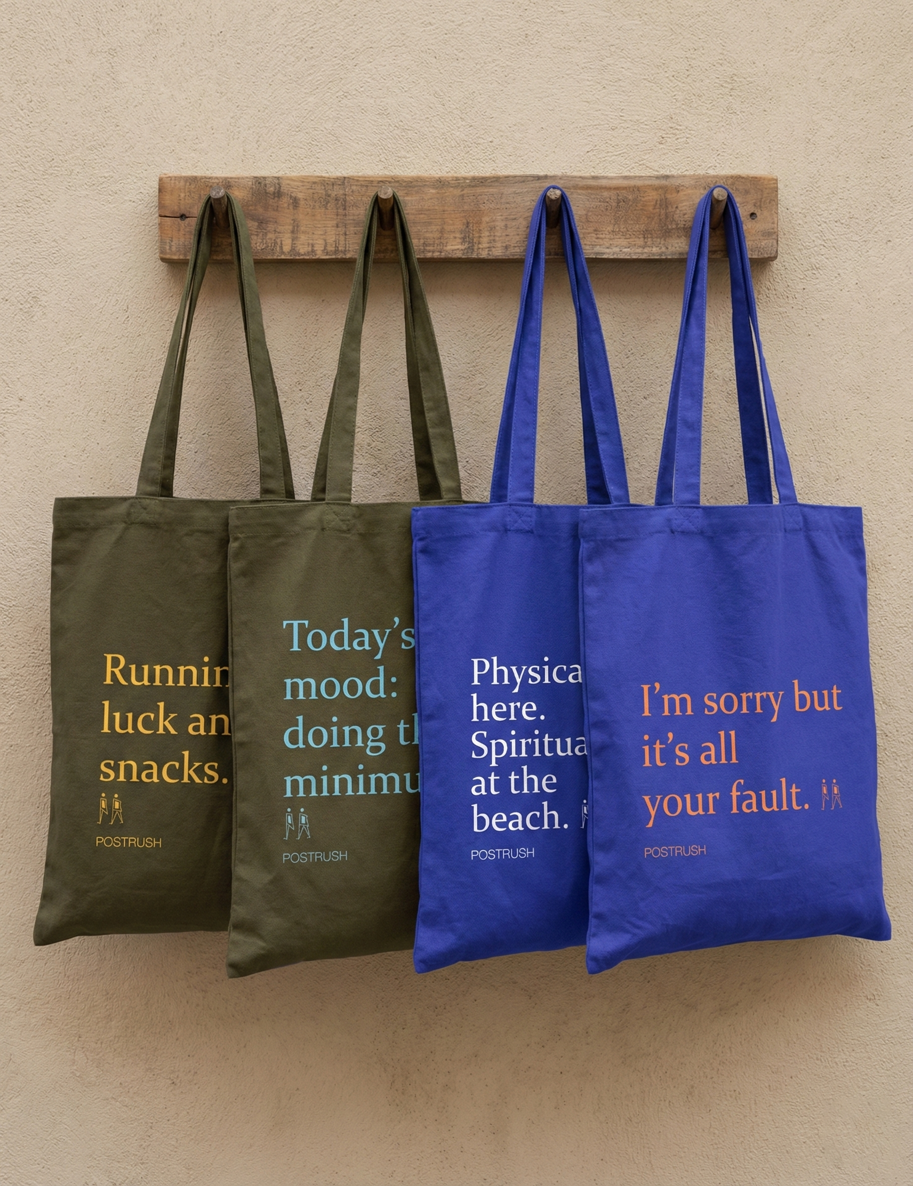 Two brown and two blue tote bags with humorous text on a wooden rack against a beige wall.