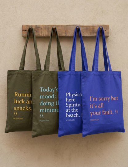 Two brown and two blue tote bags with humorous text on a wooden rack against a beige wall.