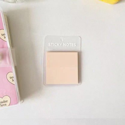 Translucent pink sticky notes placed on a clean white desk in a simple, minimal stationery setup.