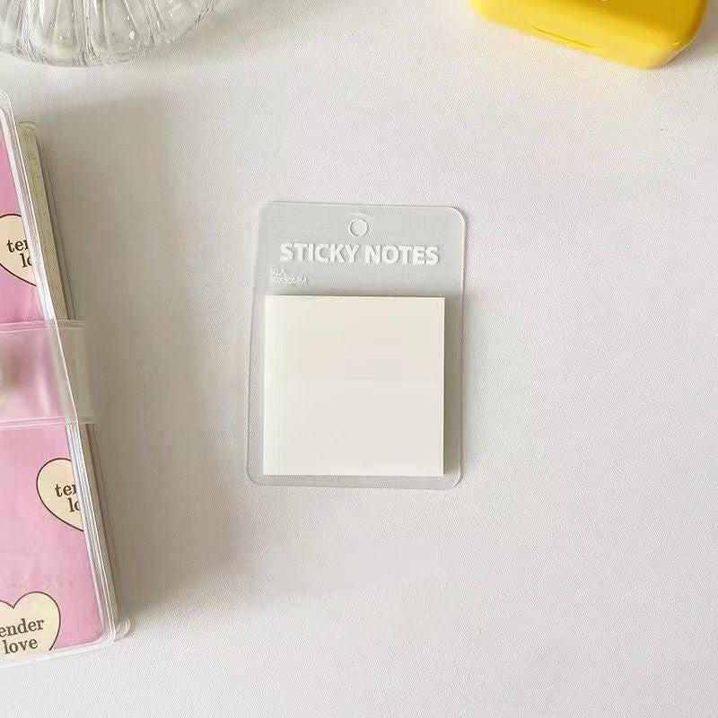 Translucent white sticky notes placed on a clean white desk in a simple, minimal stationery setup.