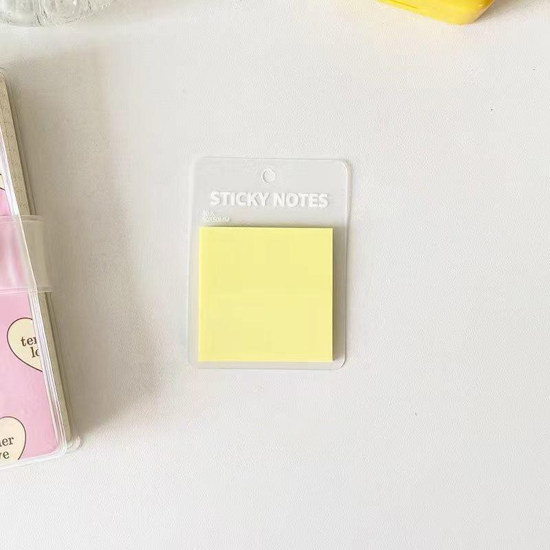 Translucent yellow sticky notes placed on a clean white desk in a simple, minimal stationery setup.